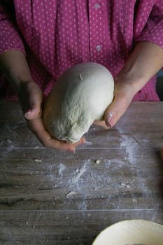 Women's hands mix the dough on a wooden table. Preparing bread for baking. Front views