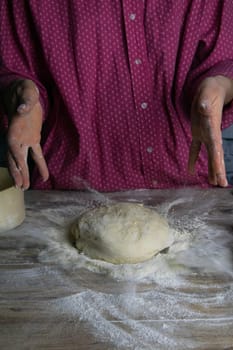 Women's hands mix the dough on a wooden table. Preparing bread for baking. Front views