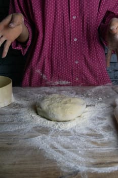 Women's hands mix the dough on a wooden table. Preparing bread for baking. Front views