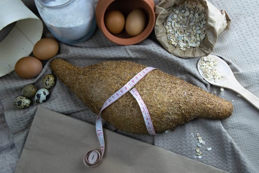 Crisp oatmeal bread wrapped with a measuring tape with i'm yits and oatmeal in the background. Top views with clear space