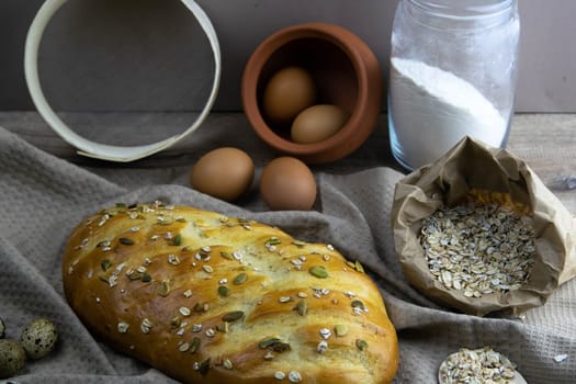 Concept shot of spice bread sticks with a wooden spoon on the wood table, oatmeal and a skein of bag thread, egg, flour, seeds and nuts. Front views