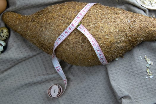 Crisp oatmeal bread wrapped with a measuring tape with i'm yits and oatmeal in the background. Top views with clear space