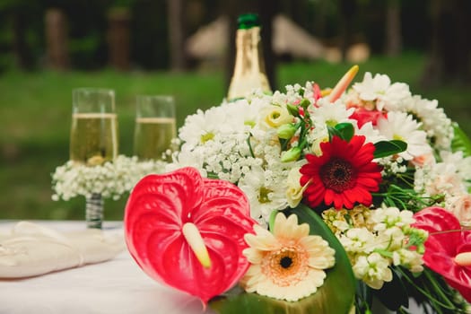 Wedding ceremony in a beautiful garden. The bride's bouquet. Champagne and two glasses