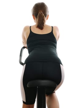 Young woman riding on a spinning bicycle from back view
