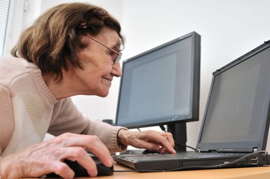 80-something senior woman working with laptop, another computer in the background