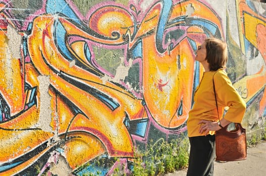 Senior woman looking at colourful graffiti wall