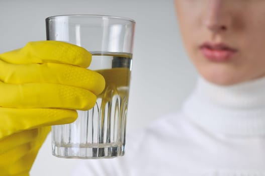Young woman in yellow hygienic gloves holding glass of water - concentration