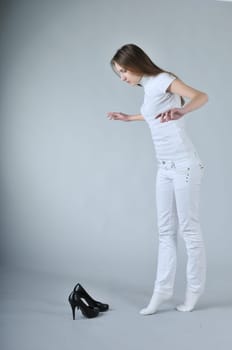 Young woman balancing on toes with high heels shoes placed on floor