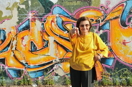 Senior woman standing at colourful graffiti wall