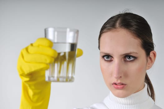 Young woman in yellow hygienic gloves holding glass of water - concentration