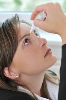 Eyes health care - detail of young woman applying eye drops