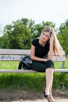 Young beautiful woman siting on bench in park in depression