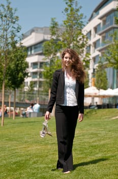 Young business woman walking barefoot outdoors in grass next to her office