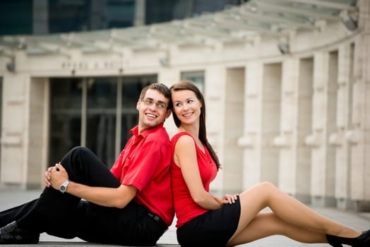 Young business couple relaxing leant with backs on street