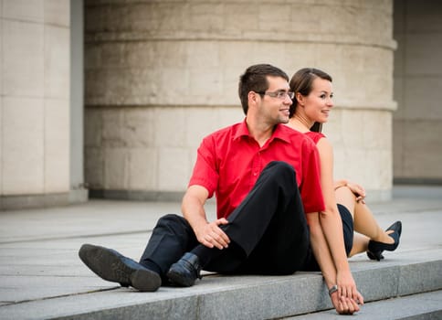 Young business couple relaxing leant with backs on street