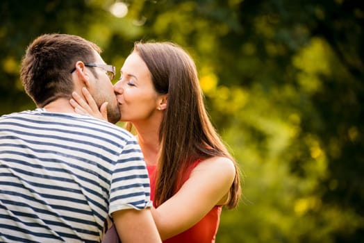 Romantic young couple kissing outdoor in nature