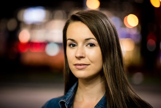 Portrait of young woman outdoor in street - neon lights in background