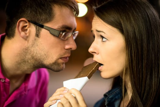 Restricted use - man looks badly on woman eating chocolate