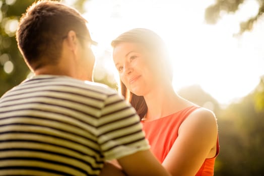 Intimate moments - young couple hugging in nature against sun