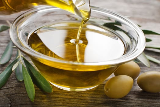 Bottle pouring virgin olive oil in a bowl close up