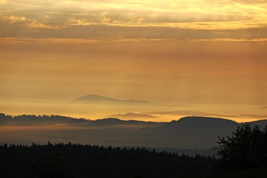Wooded hills of Giant Mountains in the morning sun and fog, Czech Republic