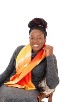 A beautiful African American woman sitting in a chair with a colorful.scarf around her neck, smiling, isolated for white background.