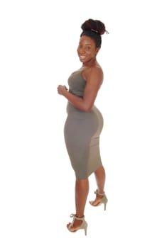 A beautiful young curvy African American female standing in a tight.gray dress, showing her figure, isolated for white background.