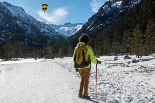 hiker looking a snowy landscape with hot air balloon in the french Pyrenees mountains