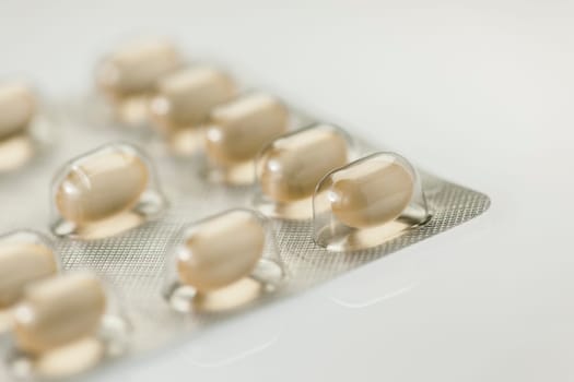 Close-up of a foil packaging for tablet dragees isolated on white background and slight reflection on the surface.