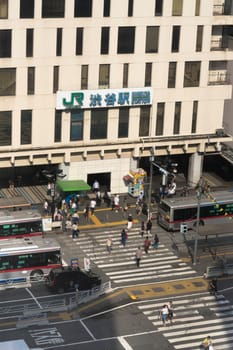 View of the southern exit of Shibuya Station, famous for its moai statue, with buses and taxis stopped at the bus terminal
