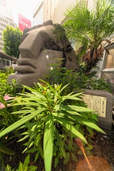 Statue of a Moai head surrounded by tropical flowers at the west exit of Shibuya Station in Tokyo, Japan. This statue was donated in 1980 by the prefecture of Nijima island of Izu archipelago to commemorate the 100 years of the transfer of the island in Tokyo Prefecture.