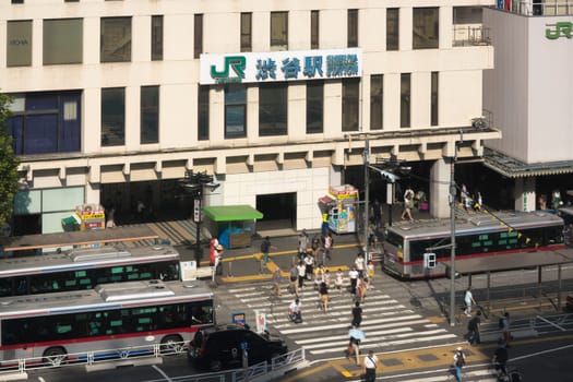 View of the southern exit of Shibuya Station, famous for its moai statue, with buses and taxis stopped at the bus terminal