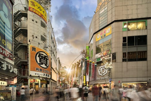 Sunset sky on Shibuya Center Gai Street which literally means Shibuya Central District. The busiest street once intersected with Shibuya Station, it stretches for 350 meters and incorporates the adjacent streets of Bunkamura, Inokashira and Utagawa into its neighborhood. In 2011 the street was renamed Basketball Street in reference to the holy place of Japanese basketball which is the Yoyogi National Gymnasium to which this street leads. The photo is taken in summer at the Tanabata Star Festival where the portal is adorned with paper decorations in the shape of shooting stars for the occasion.