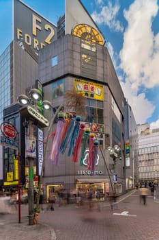 Summer blue sky on Shibuya Center Gai Street which literally means Shibuya Central District. The busiest street once intersected with Shibuya Station, it stretches for 350 meters and incorporates the adjacent streets of Bunkamura, Inokashira and Utagawa into its neighborhood. In 2011 the street was renamed Basketball Street in reference to the holy place of Japanese basketball which is the Yoyogi National Gymnasium to which this street leads. The photo is taken in summer at the Tanabata Star Festival where the portal is adorned with paper decorations in the shape of shooting stars for the occasion.