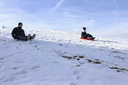 A woman and a man riding a snowmobile down a mountain in winter