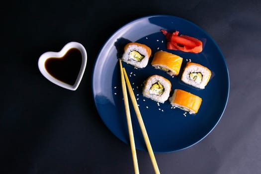 Top view of wooden platter with great set of delicious Nigiri sushi and Tempura rolls with Maki and Uramaki rolls on an orange background. Front views
