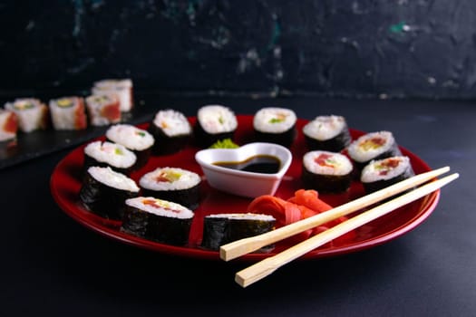 Top view of wooden platter with great set of delicious Nigiri sushi and Tempura rolls with Maki and Uramaki rolls on an orange background. Front views