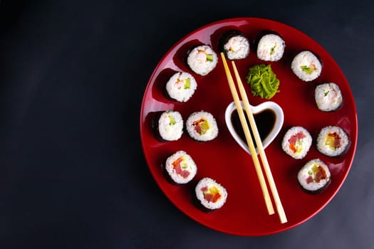 Top view of wooden platter with great set of delicious Nigiri sushi and Tempura rolls with Maki and Uramaki rolls on an orange background. Front views