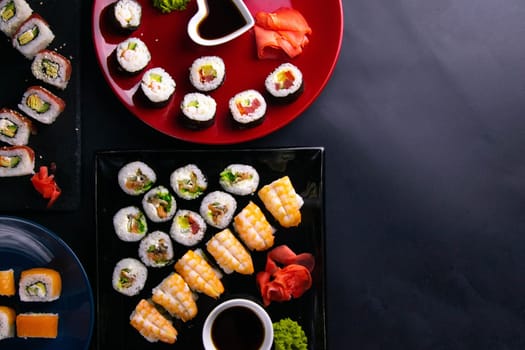Top view of wooden platter with great set of delicious Nigiri sushi and Tempura rolls with Maki and Uramaki rolls on an orange background. Front views