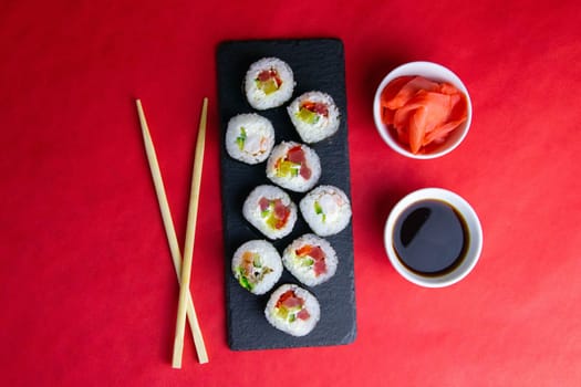 Top view of wooden platter with great set of delicious Nigiri sushi and Tempura rolls with Maki and Uramaki rolls on an rad background. Top views