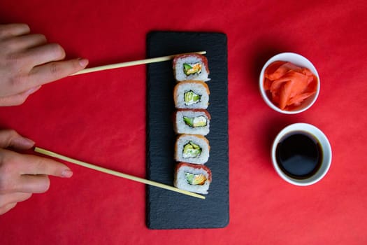 Top view of wooden platter with great set of delicious Nigiri sushi and Tempura rolls with Maki and Uramaki rolls on an rad background. Top views