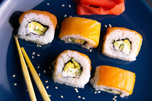 Top view of wooden platter with great set of delicious Nigiri sushi and Tempura rolls with Maki and Uramaki rolls on an orange background. Front views