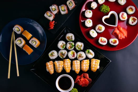 Top view of wooden platter with great set of delicious Nigiri sushi and Tempura rolls with Maki and Uramaki rolls on an orange background. Front views