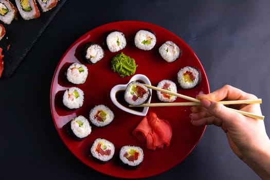 Top view of wooden platter with great set of delicious Nigiri sushi and Tempura rolls with Maki and Uramaki rolls on an orange background. Front views