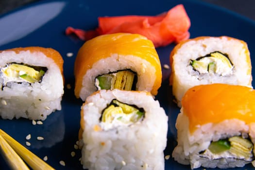 Top view of wooden platter with great set of delicious Nigiri sushi and Tempura rolls with Maki and Uramaki rolls on an orange background. Front views