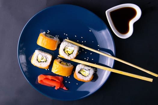 Top view of wooden platter with great set of delicious Nigiri sushi and Tempura rolls with Maki and Uramaki rolls on an orange background. Front views