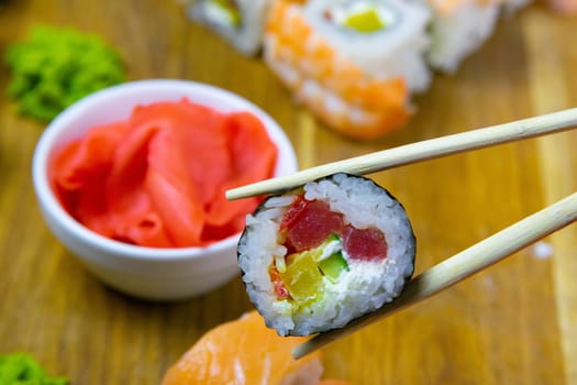 Top view of wooden platter with great set of delicious Nigiri sushi and Tempura rolls with Maki and Uramaki rolls on an rad background. Top views