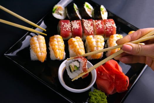 Top view of wooden platter with great set of delicious Nigiri sushi and Tempura rolls with Maki and Uramaki rolls on an rad background. Top views