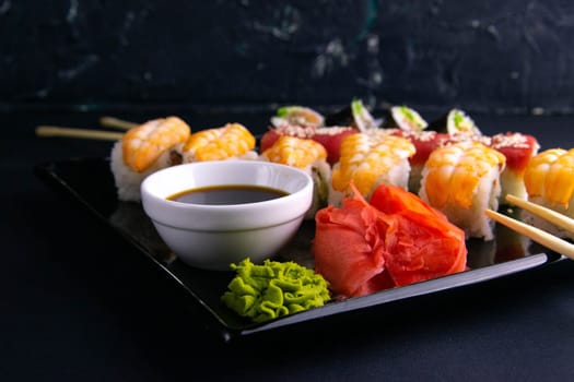 Top view of wooden platter with great set of delicious Nigiri sushi and Tempura rolls with Maki and Uramaki rolls on an rad background. Top views