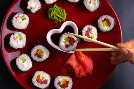 Top view of wooden platter with great set of delicious Nigiri sushi and Tempura rolls with Maki and Uramaki rolls on an orange background. Front views